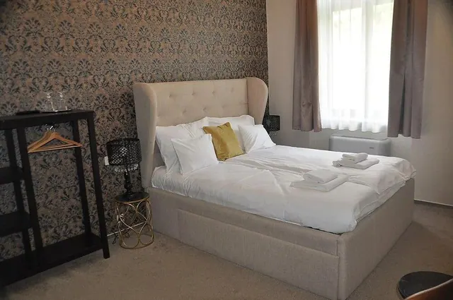 Az Arch Hotel egyik szobája kárpitozott ággyal és mintás tapétával